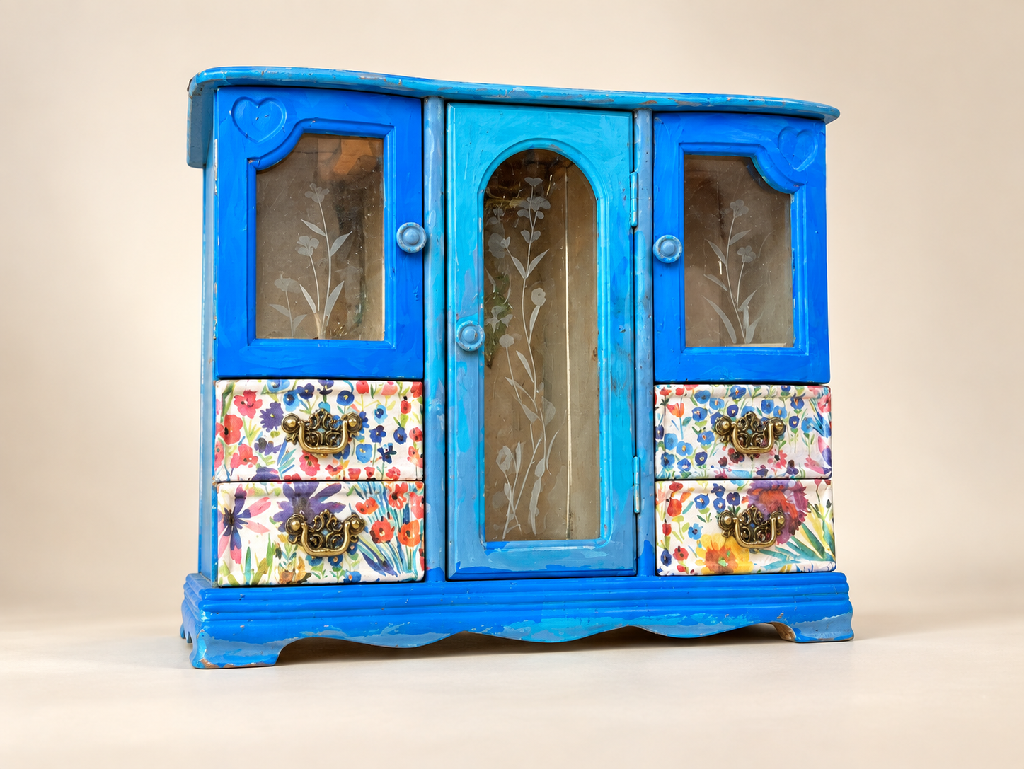 Front of a blue upcycled jewelry cabinet with floral drawers and etched glass doors